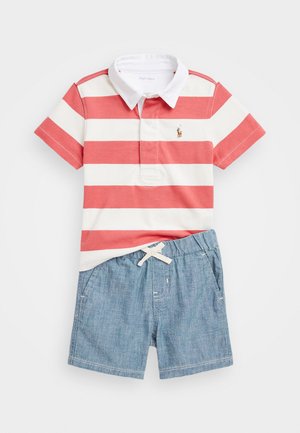 Červené a biele pruhované polo tričko s bielym golierom, v kombinácii s modrými džínsovými šortkami s šnúrkou a bočnými vreckami.