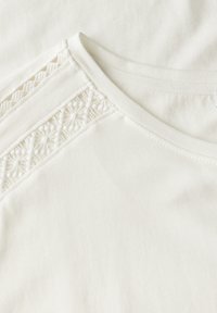 Hvid bomulds T-shirt med et dekorativt, tekstureret blondepanel på skulderen. Glat stof med et klassisk rundhalset design.