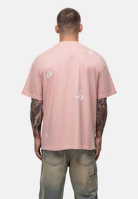 T-shirt rose à manches courtes avec une broderie de papillon blanche dans le dos. Fabriqué en tissu doux avec une coupe décontractée.