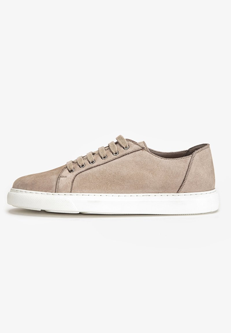 Baskets basses en daim beige avec lacets beiges, œillets argentés et semelle épaisse en caoutchouc blanc sur fond blanc.