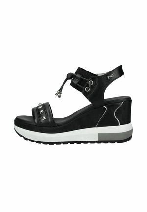 Sandalo zeppa nero con cinturino anteriore borchiato, cinturino alla caviglia regolabile con coulisse e suola platform bianca e grigia.