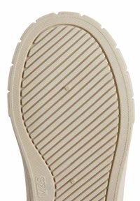 Semelle de chaussure couleur crème avec des rainures horizontales et des accents circulaires. Surface texturée pour une meilleure adhérence, avec des bords prononcés et une forme arrondie.