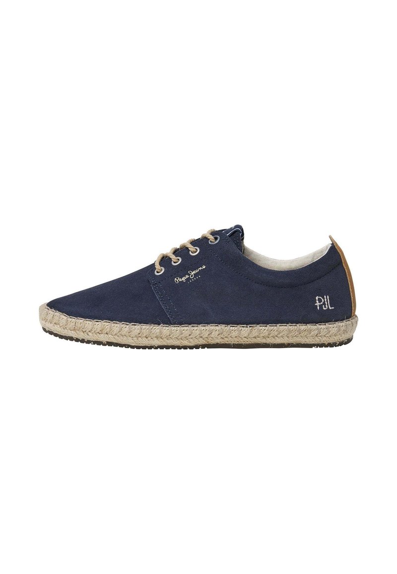 Zapato espadrille de lona azul marino con suela de yute texturizado beige, punta redonda y ojales. Presenta el logo en el lateral y un acento de talón en marrón.