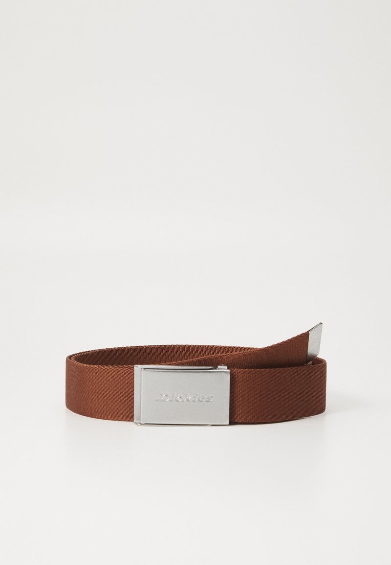Ceinture en tissu marron avec une boucle rectangulaire argentée gravée « Dickies », enroulée sur une surface blanche.