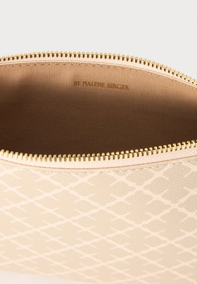Pochette beige à motifs avec fermeture éclair dorée, ouverte pour montrer la doublure intérieure en tissu marron clair uni.