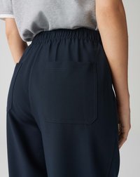 Pantalons bleu marine avec une taille élastique froncée, dotés de deux poches arrière et d'une texture de tissu lisse.