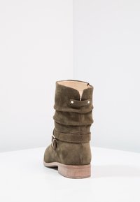 Bottine en daim vert à design décontracté, avec un accent bouclé et un talon en bois, dotée d'une doublure intérieure lisse et d'une surface extérieure texturée.