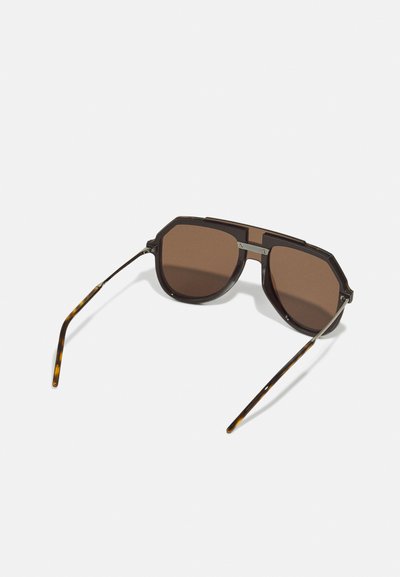 Brown tinted octagonal sunglasses with a dark frame and subtle tortoiseshell accents on the temples. Stainless steel detailing on the bridge.