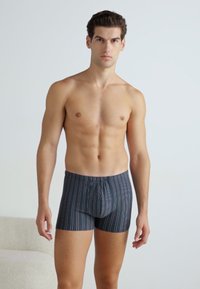 Boxers azuis-escuros com riscas, apresentando linhas horizontais multicoloridas, com um cós elástico suave e um design ajustado.