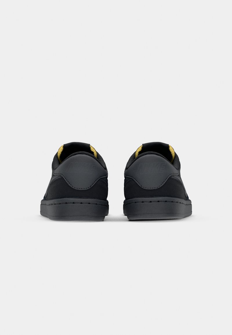 Schwarze Sportschuhe mit Obermaterial aus Wildleder und Synthetik, runder Zehenpartie und gelben Innenakzenten. Verfügt über eine Naht rund um die Sohle und die Ferse.