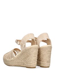 Sandalias de cuña beige con tacón de cuerda trenzada y correas de tela texturizada. Tira ajustable en el tobillo con un patrón a cuadros.