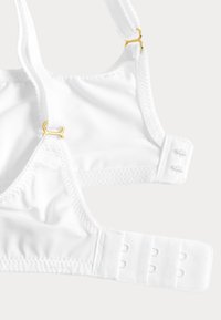Witte zachte stoffen bh met verstelbare bandjes met gouden hardware en een achterkant met drie rijen haakjes.