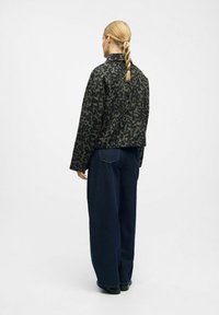 Leopard print cropped jacket in dark tones, paired with loose dark denim trousers. Features a collared neckline and relaxed fit.