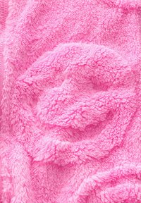 Couverture rose floue avec une texture douce, présentant un design en tourbillon et une apparence lisse et pelucheuse. Les bords peuvent inclure des coutures.