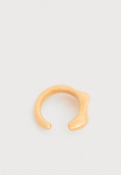 Ανοιχτό δαχτυλίδι σε χρυσό τόνο με ομαλό, στρογγυλεμένο σχέδιο και ασύμμετρο σχήμα σε μία άκρη, σε απλό λευκό φόντο.