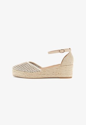 Zapato cuña tipo espadrille tejido en beige con puntera cerrada, correa en el tobillo y suela trenzada de yute.