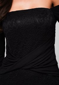 Abito nero con bustier in pizzo e maniche a spalla scoperta. Presenta tessuto arricciato alla vita e un motivo testurizzato intricato.