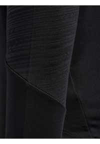 Svart atletisk långärmad tröja med ett texturerat mönster på överarmen, slät tyg och figurnära design med kontrasterande sömlösa detaljer.