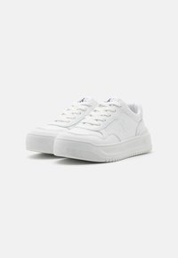 Sneakers bianchi con una superficie in pelle liscia, suole testurizzate, punta rotonda e lacci piatti. Presenta un logo discreto sul lato e sulla linguetta.