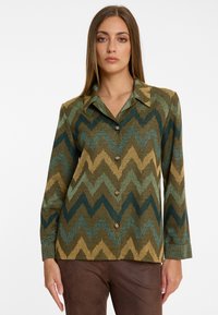 Hemd mit Knopfleiste und einem Zickzack-Muster in Grün, Gold und Dunkelblau. Aus strukturiertem Stoff, mit einem spitzen Kragen und langen Ärmeln.