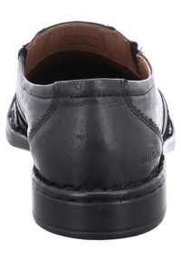 Černá kožená bota s hladkým povrchem, nízkým podpatkem a zakřivenou patou. Obsahuje švy a hnědou podšívku.