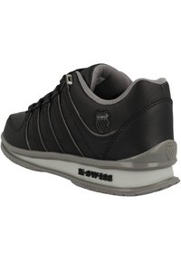 Černé kožené tenisky s šedými akcenty, které mají silné šněrování, polstrovaný límec a výraznou gumovou podrážku s logem "K-Swiss".