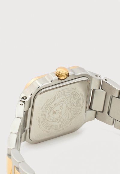 Nerūdijančio plieno laikrodžio nugarėlė su išgraviruotu Medūzos galvos logotipu, dviejų tonų metalinė apyrankė, auksinė karūnėlė ir išgraviruotas tekstas, įskaitant safyro kristalą ir pagaminta Šveicarijoje.