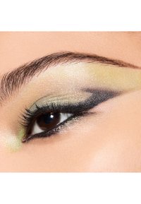Nahaufnahme eines Auges mit metallischem gelbem und grünem Lidschatten, definiertem schwarzen Eyeliner und langen Wimpern. Eine glatte Hautstruktur umgibt das Auge.