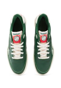 Zöld bőrsneakerek fehér fűzőkkel és krémszínű részletekkel. Perforált orrú, Reebok logóval és teniszlabda grafikával a nyelvén.