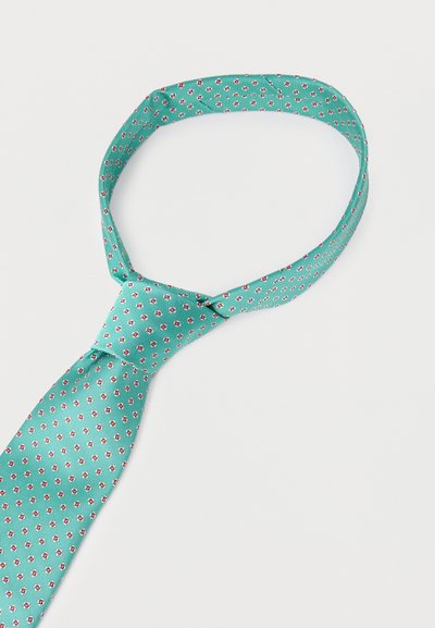 Φωτεινά πράσινη γραβάτα με μικρό κόκκινο και λευκό ανθικό μοτίβο, χαλαρά δεμένη σε λευκό φόντο.