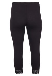 Leggings noirs avec une texture lisse, ornés de détails en dentelle aux poignets. Le design est ajusté, avec une taille haute pour le confort.