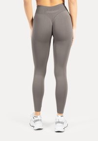 Grå leggings med høj talje, glat tekstur og tætsiddende pasform, med sømdetaljer og et præget logo ved taljen.