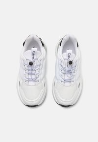 Bijele atletske tenisice imaju gornji dio od mrežastog i tekstilnog materijala, okrugle vezice, brandiranu petlju za povlačenje i crne akcentne detalje na peti.