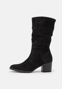 Botte noire en suede, montée jusqu'au genou, avec un design ample, un bout arrondi et un talon en bloc robuste. Elle présente une texture lisse et douce.
