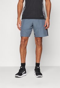 Men’s grå treningsshorts med elastisk midje, strukturert stoff, sidet lommer og en liten oransje logo på kanten.
