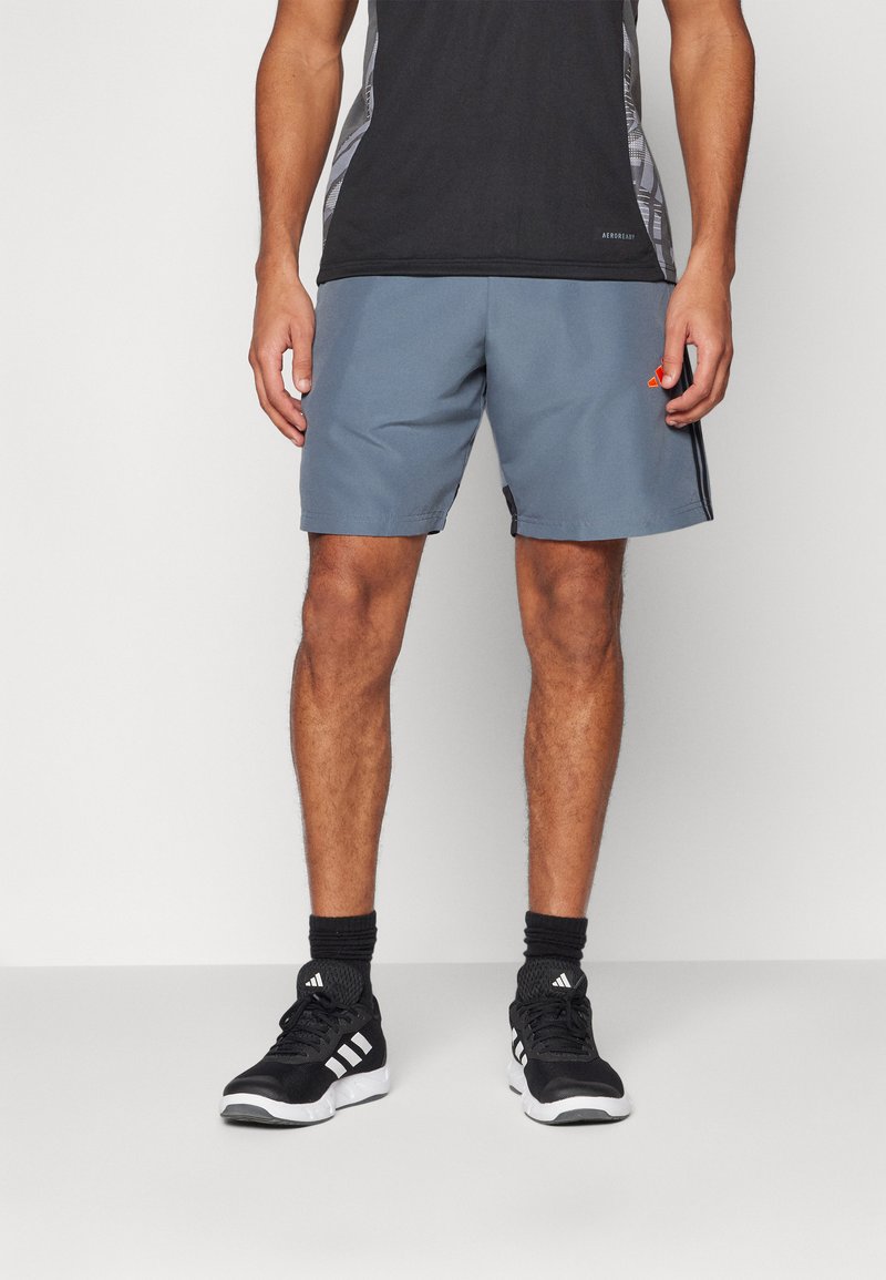 Men’s grå treningsshorts med elastisk midje, strukturert stoff, sidet lommer og en liten oransje logo på kanten.