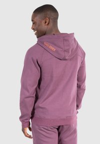 Felpa con cappuccio viola dalla vestibilità comoda, tessuto testurizzato, polsini a costine e logo "SMILODOX" sulla schiena. Finitura liscia.