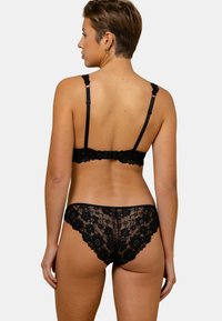 Ensemble de lingerie en dentelle noire comprenant un soutien-gorge et un slip avec des motifs floraux, des bretelles ajustables et une fermeture à crochets sur le soutien-gorge. Texture en dentelle douce et transparente.
