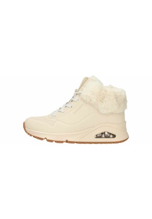 Sneaker bianco con colletto peloso, tomaia texture, design con lacci e un'unità di ammortizzazione visibile nella suola. Suola in gomma marrone.