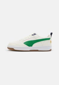 Weißer Sneaker mit grünen Akzenten, Obermaterial aus Leder, perforierte Zehenpartie und beige Gummisohle. Verfügt über einen blauen Fersenbereich und ein Logo an der Seite.