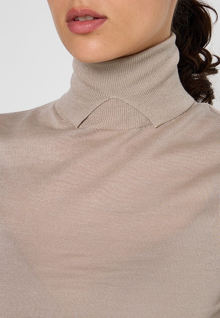 Beiger Rollkragenpullover mit gerippter Textur und figurbetontem Design, ausgestattet mit einem umgeschlagenen Kragen und glatter Oberfläche, ideal zum Layering.