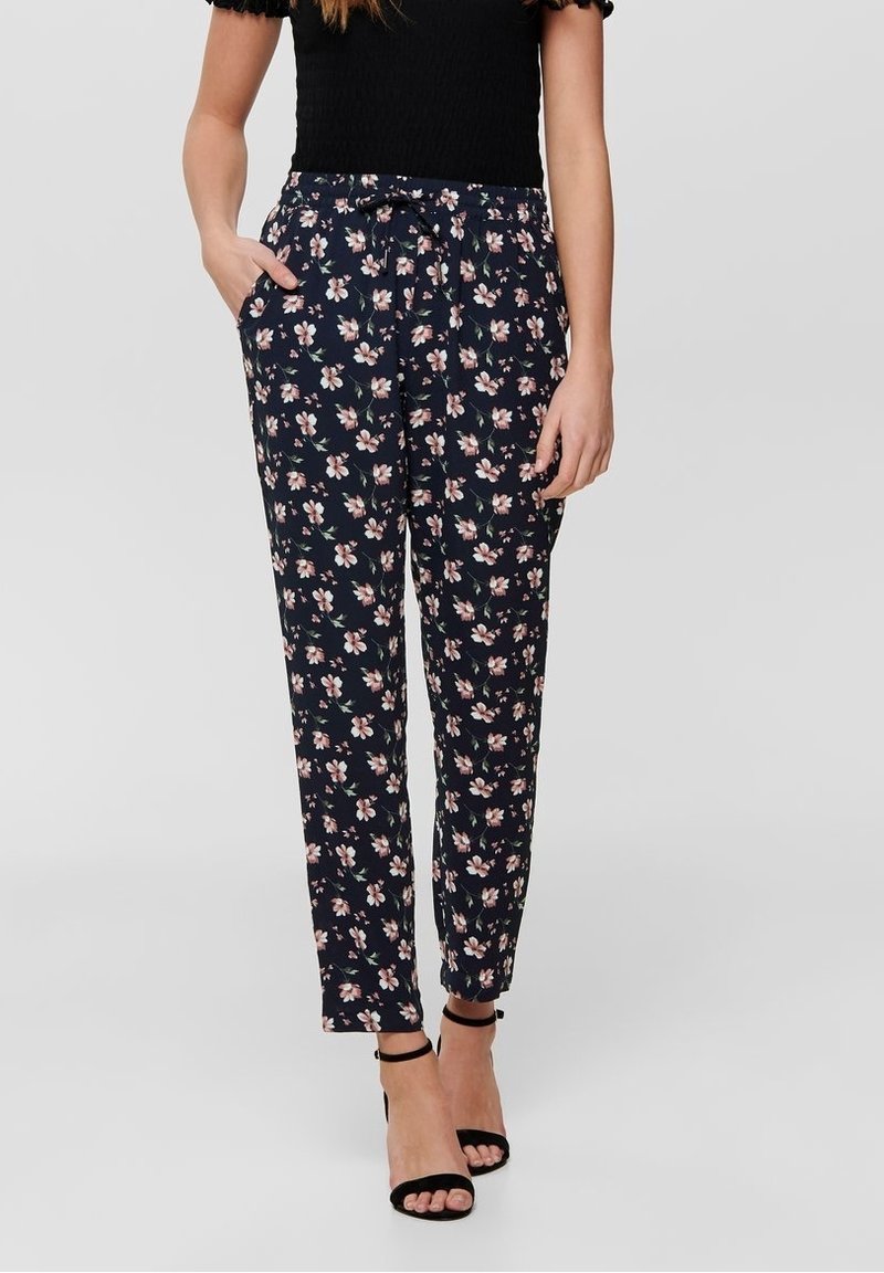 Pantalon floral marine avec des fleurs roses et blanches, taille élastique, poches avant et coupe fuselée aux chevilles. Le tissu a une texture lisse.