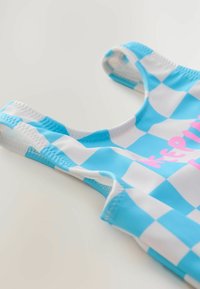 Maillot de bain à carreaux bleus et blancs avec un décolleté en scoop et un texte rose. Caractéristiques d'un tissu lisse avec des bords cousus et des bretelles.