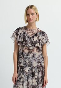Blusa trasparente con maniche a volant, scollatura a forma di V e un motivo astratto in tonalità terrose di beige, marrone e grigio.