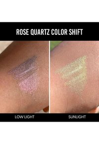 Campione di colorazione Rose Quartz Color Shift, che mostra una tonalità rosata in luce bassa e una sfumatura verdastra alla luce del sole su una pelle texturizzata.