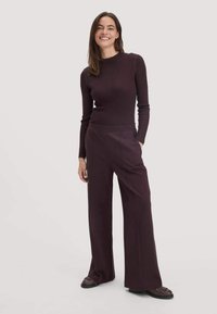 Geribbeld, lang mouw, donkerpaars topje gecombineerd met wijde, bijpassende broek. De outfit heeft een eenvoudig, aansluitend ontwerp met een gladde stof.