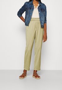 Jeansowa kurtka, kremowa bluzka, jasnobrązowe spodnie z elastycznym pasem, brązowe espadryle. Cechy obejmują detale z guzikami i lekkie tekstury.