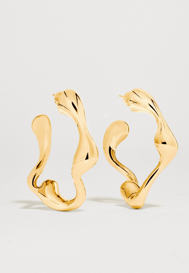 Asymmetrical wavy gold-tone hoop earrings with a polished, reflective finish on a plain light background.