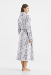 Grau gewand mit einem weichen, strukturierten Stoff, der ein Muster aus Schleifen aufweist. Es hat einen Schalkragen, lange Ärmel und einen Taillengürtel.