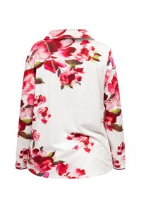 Blouse met lange mouwen en een witte achtergrond, versierd met een levendig bloemenpatroon in tinten van rood en roze. Zachte stof met een kraag.